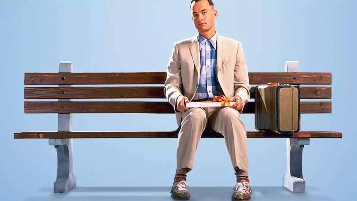 مشهد من فيلم Forrest Gump يظهر البطل جالسًا على مقعد خشبي في الحديقة، فيلم مناسب لتعلم اللغة الإنجليزية للمبتدئين مع ترجمة عربية.
